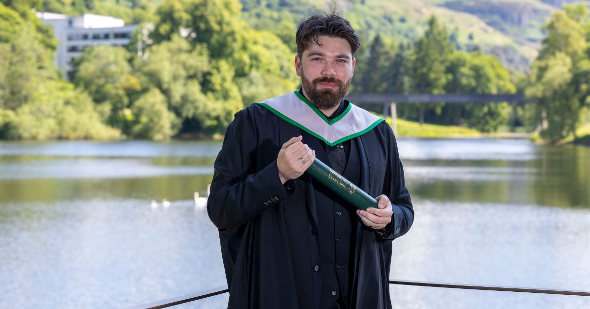 Dechlan Nicoll graduate from the University of Stirling in Psychology standing by Airthrey Loch