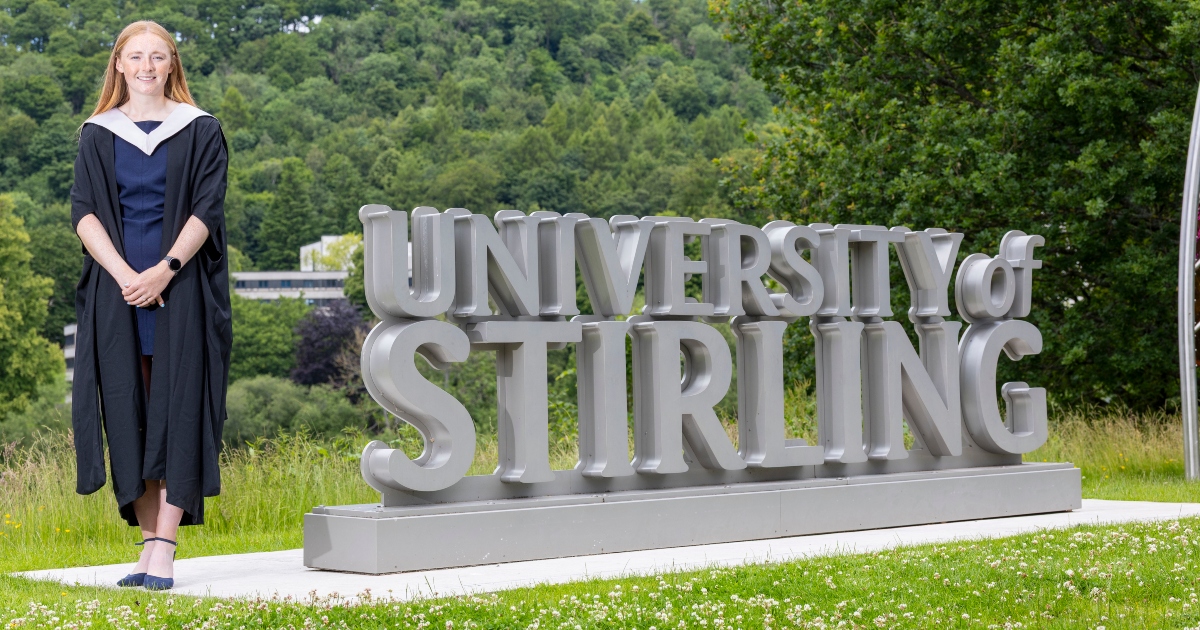 Louise Duncan stands at the University of Stirling sign.