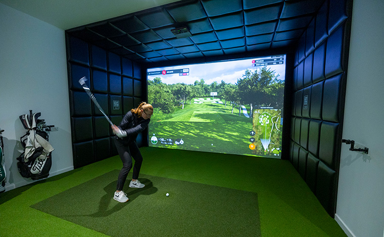 Female golfer hitting ball into golf simulator